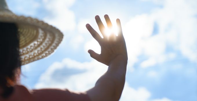 Mujer tapándose el sol de la cara con la mano